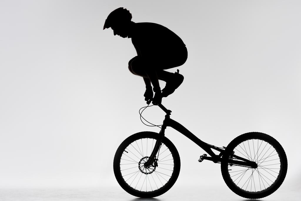 Silhouette eines Trial-Bikers, der mit weißen Händen am Lenker steht - Foto, Bild