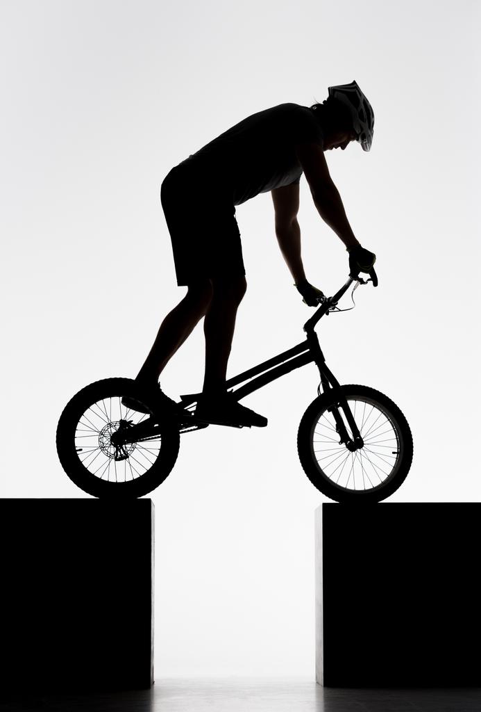 σιλουέτα του δοκιμή ποδηλάτης εξισορρόπησης σε δύο βάσεις σε λευκό - Φωτογραφία, εικόνα