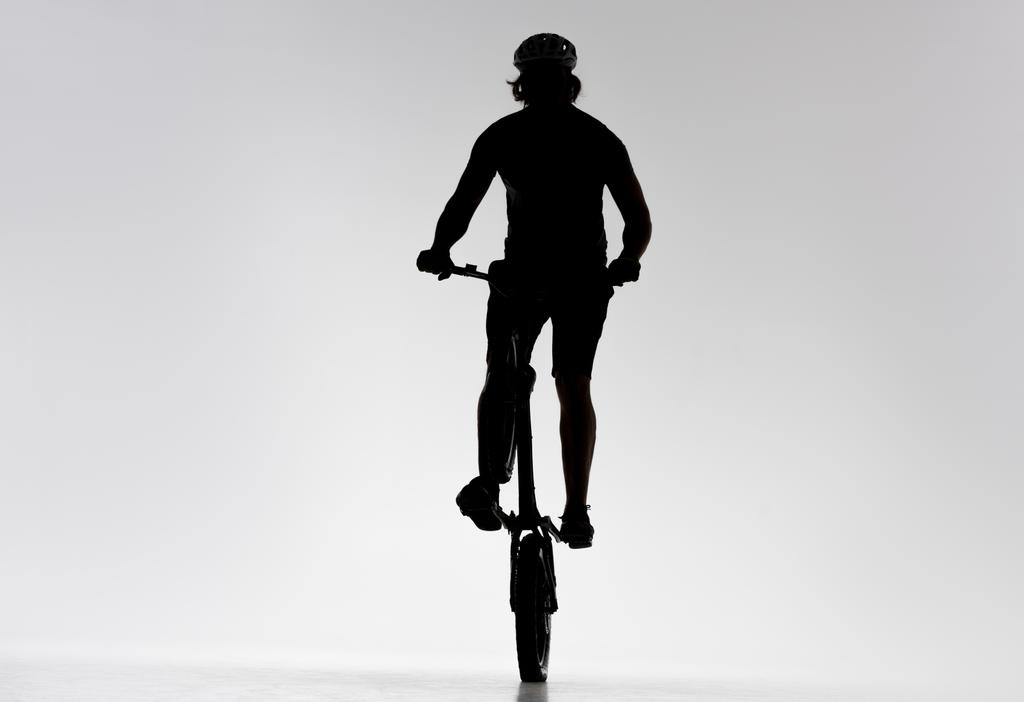 silhouet van proef biker rijden op achterwiel op wit - Foto, afbeelding