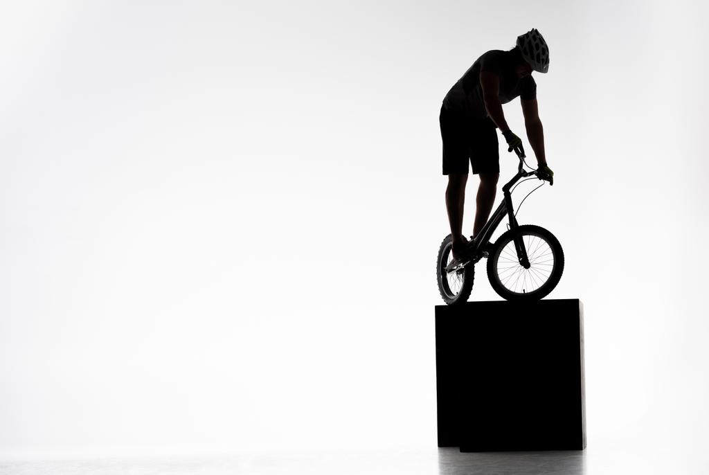 σιλουέτα του δοκιμή ποδηλάτης εξισορρόπηση σε εμπόδια στο λευκό - Φωτογραφία, εικόνα