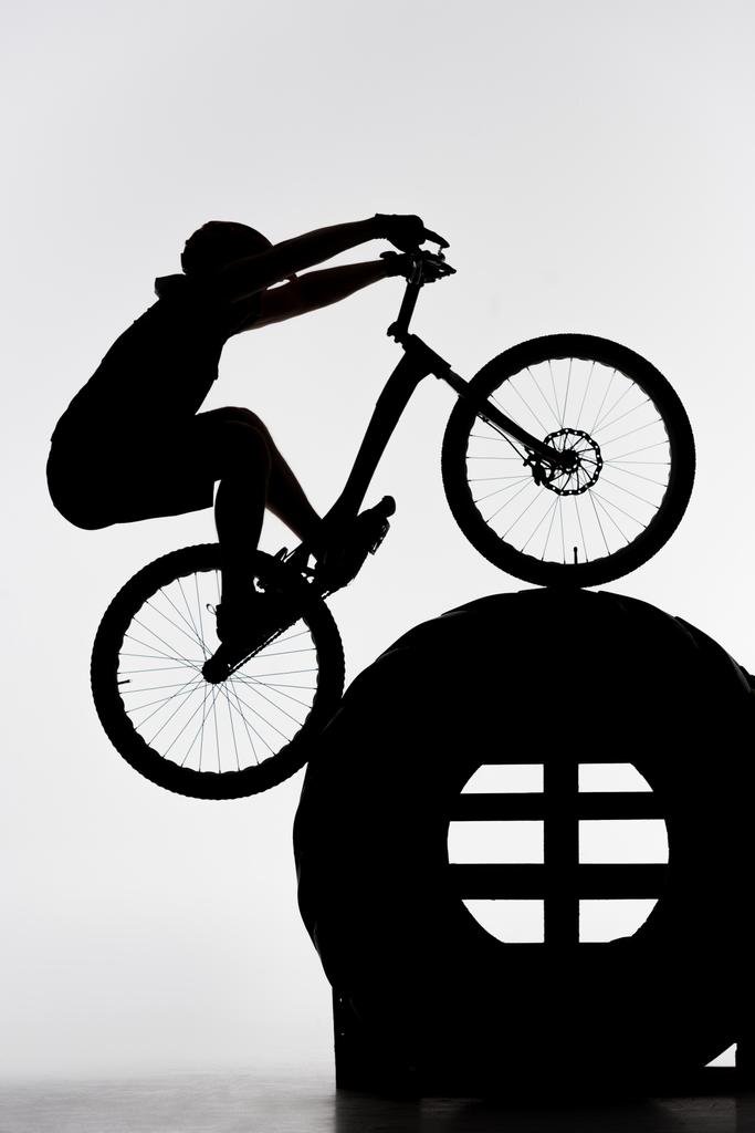 silhouette du motard d'essai équilibrage sur roue tracteur sur blanc
 - Photo, image