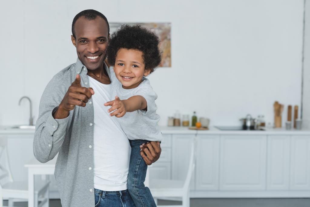 african american father and son pointing on camera at home - Photo, Image