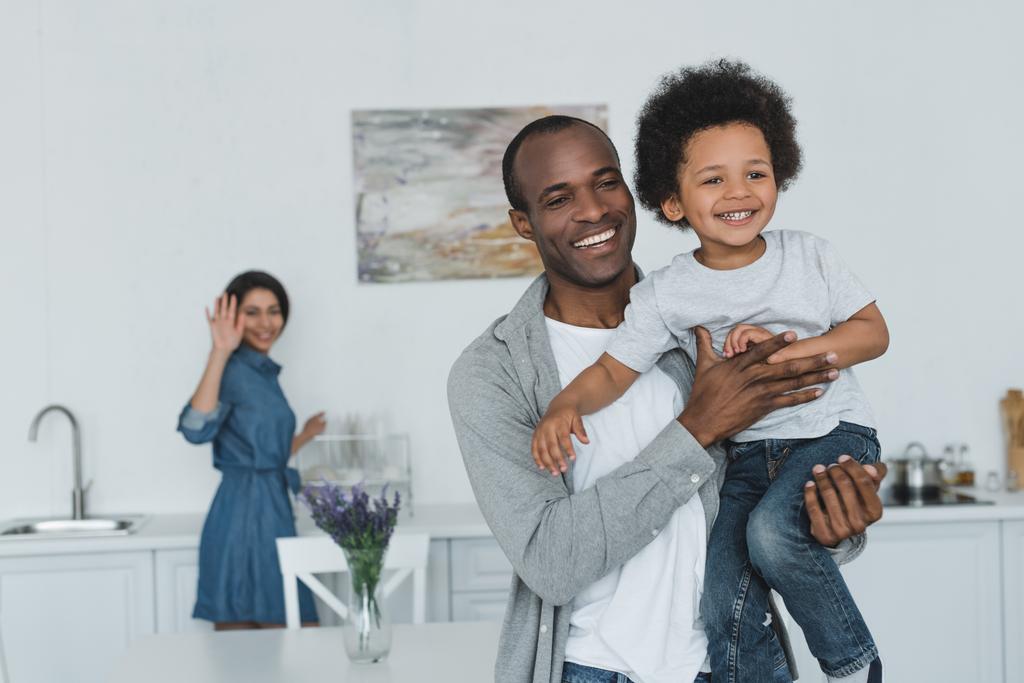 afro-amerikai apja átölelve integetett kézzel otthon anya és fia - Fotó, kép