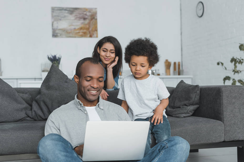 genitori afroamericani e figlio guardando il computer portatile in soggiorno
 - Foto, immagini