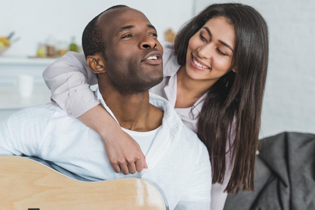 african american boyfriend playing guitar and singing for girlfriend at home - Photo, Image