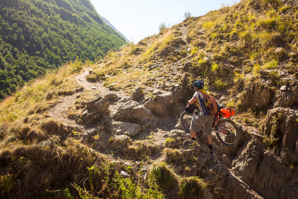 Motociclista empuja su bicicleta en las altas montañas del Cáucaso
 - Foto, Imagen