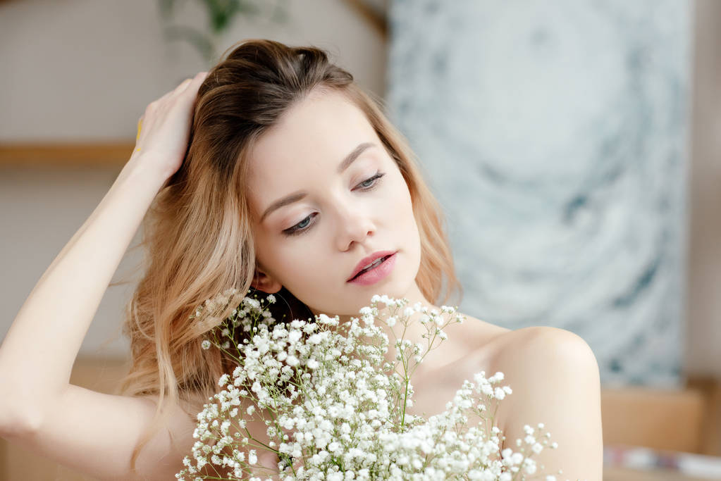 portrait de belle fille nue sensuelle tenant des fleurs blanches et regardant loin dans le studio d'art
 - Photo, image