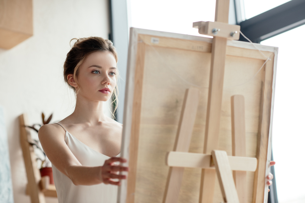 красивая молодая художница смотрит на картинку на лацкане
 - Фото, изображение