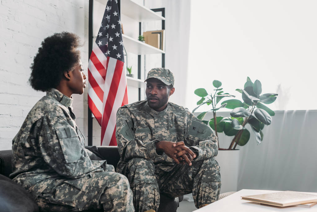 女と自宅のソファで話している軍服の男 - 写真・画像