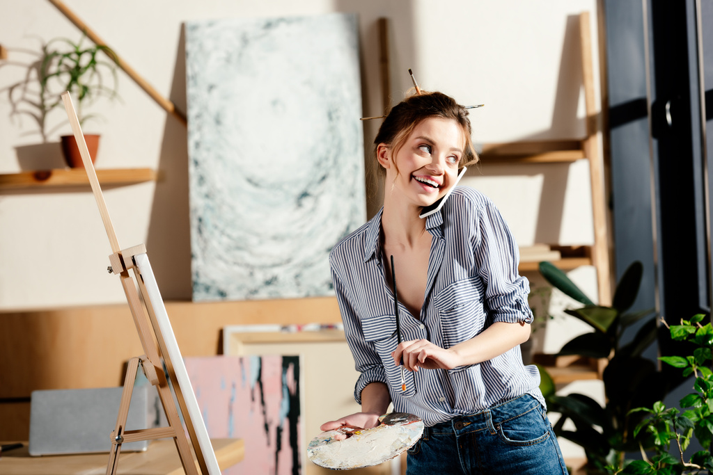 χαμογελαστή γυναίκα καλλιτέχνης μιλάει στο smartphone και το σχέδιο  - Φωτογραφία, εικόνα