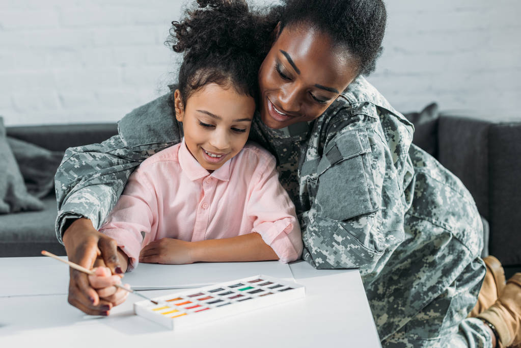 afrikanisch-amerikanische Soldatin mit Tochter zeichnet mit Aquarellfarbe - Foto, Bild
