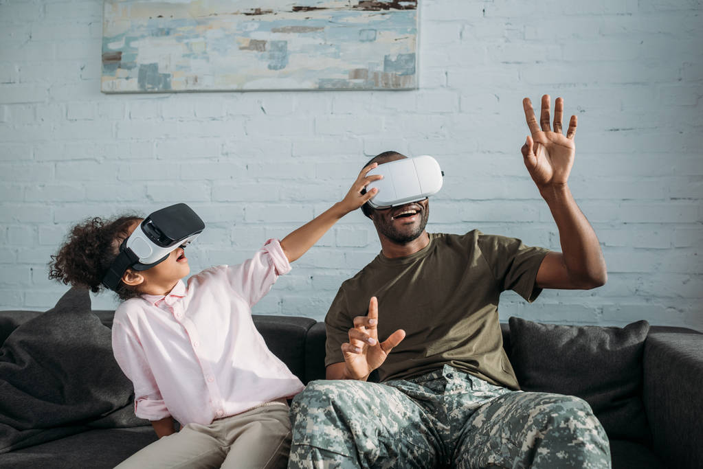 仮想現実のヘッドセットと遊ぶ子供に迷彩服でハンサムな兵士 - 写真・画像