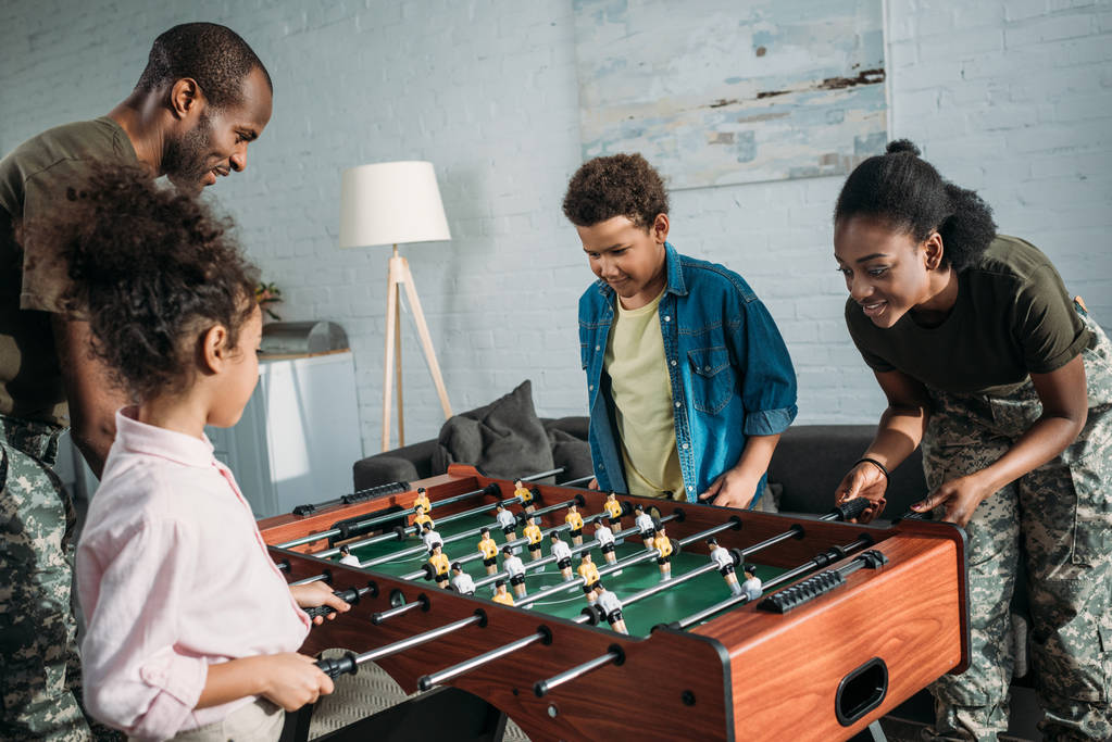 African american man and woman soldiers playing table football with their kids - Photo, Image