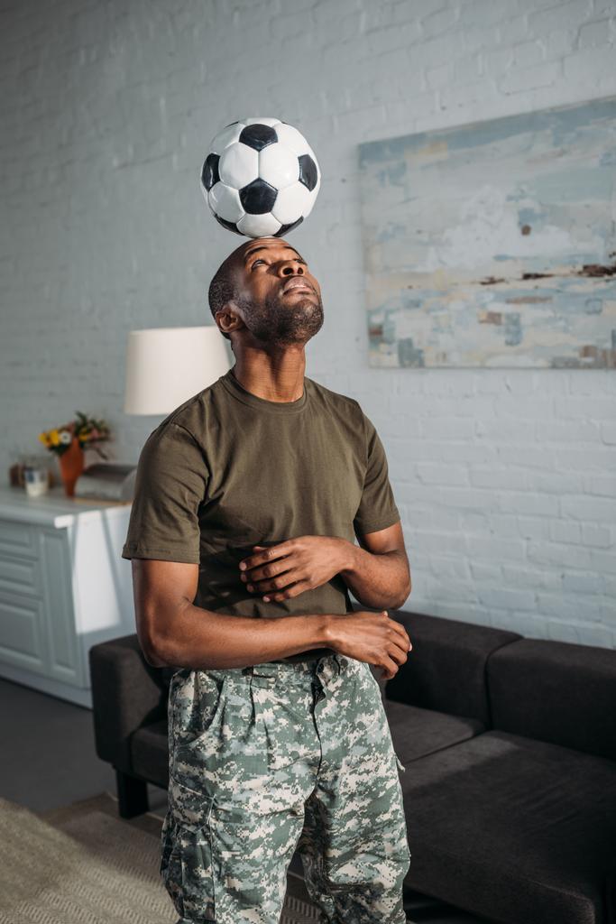 Soldado afro-americano jogando com bola de futebol na cabeça
 - Foto, Imagem