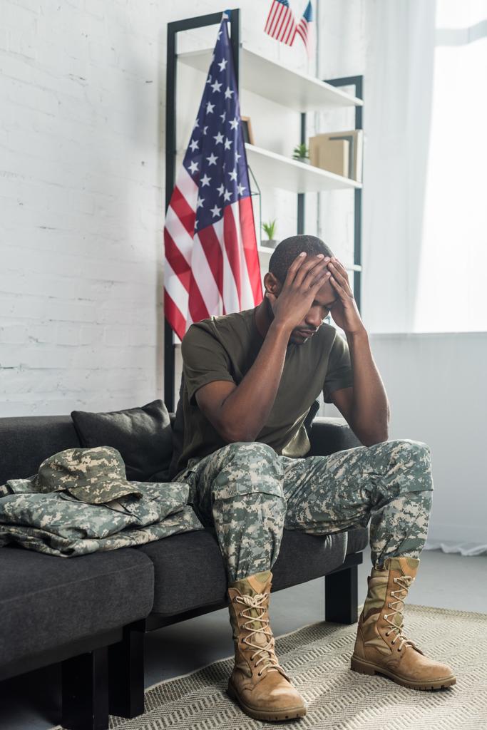 Upset army soldier sitting on sofa with camouflage clothes - Photo, Image