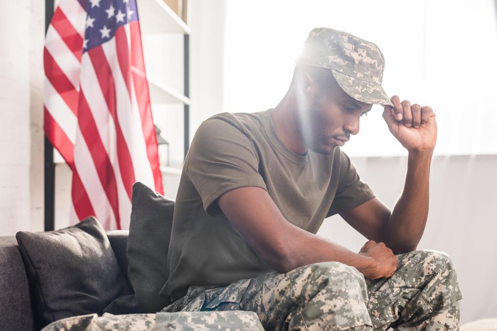 Αφρικανικός Αμερικανός στρατιώτης σε ρούχα παραλλαγής που κάθεται στον καναπέ - Φωτογραφία, εικόνα