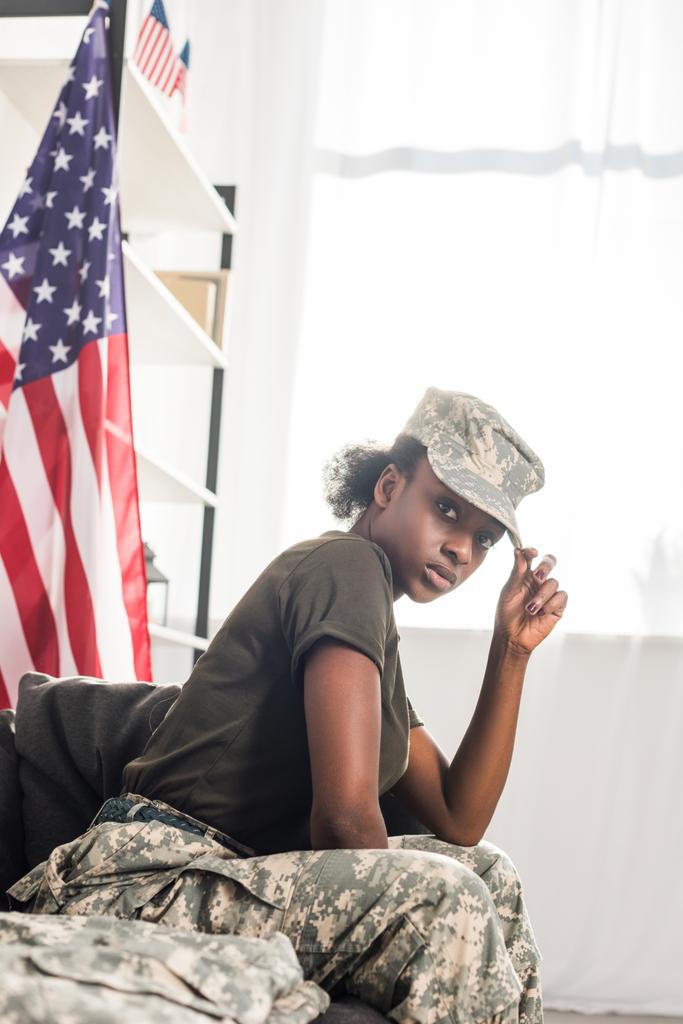 Joven soldado con ropa de camuflaje sentada en un sofá
 - Foto, imagen