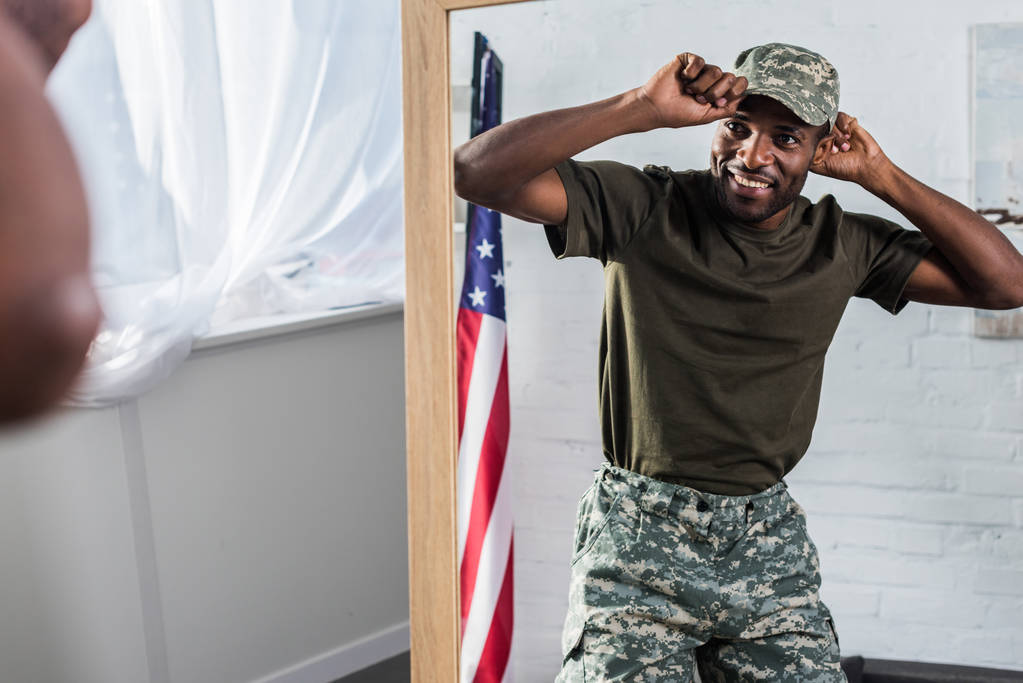 Lächelnder afrikanischer amerikanischer Soldat in Tarnkleidung posiert vor dem Spiegel - Foto, Bild