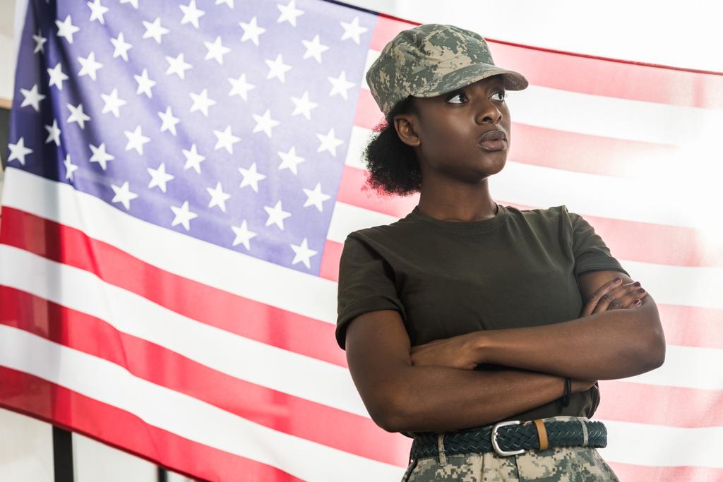 Női afro-amerikai katona terepszínű ruhák előttünk zászló - Fotó, kép