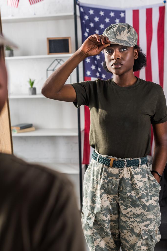 Fiatal katona terepszínű ruhák pózol a tükör által - Fotó, kép