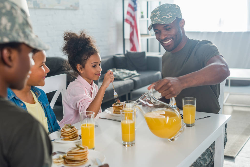 Ευτυχισμένη οικογένεια με παιδιά και γονείς σε ρούχα του στρατού απολαμβάνοντας πρωινό - Φωτογραφία, εικόνα