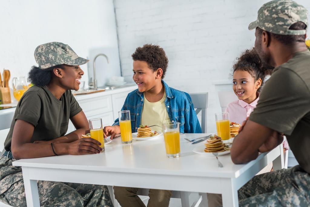 Parents in camouflage clothes with children enjoying meal in kitchen - Photo, Image