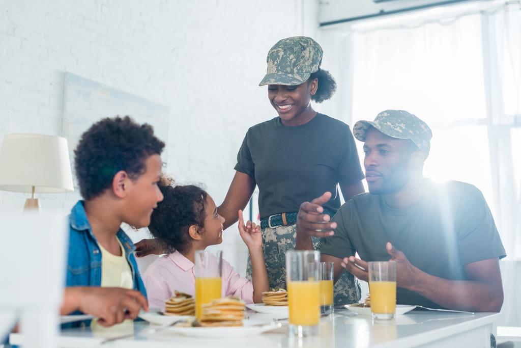 Femme et homme en uniforme militaire avec leurs enfants par table de cuisine
 - Photo, image