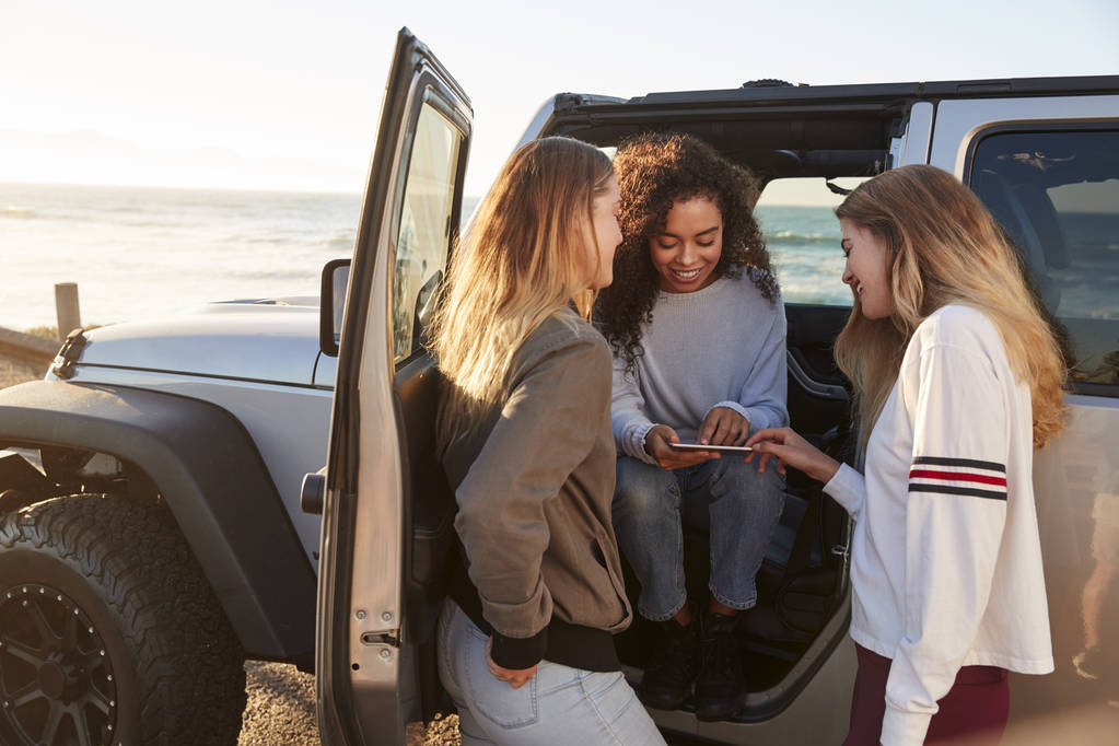 Três namoradas planejando viagem de carro com computador tablet
 - Foto, Imagem