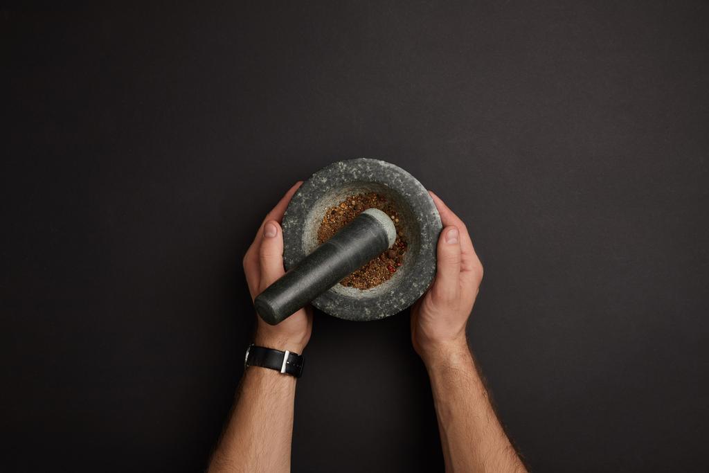 partial view of man with mortar and pestle on black surface - Photo, Image