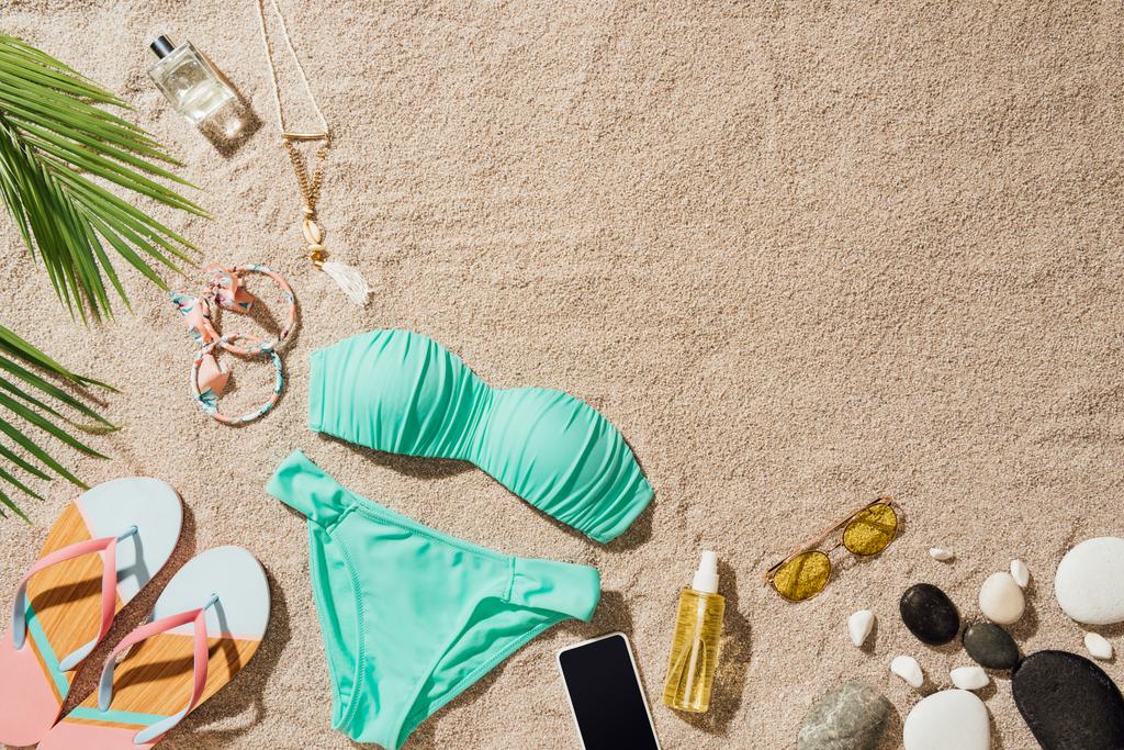 vue de dessus du bikini bleu avec divers accessoires sur la plage de sable
 - Photo, image