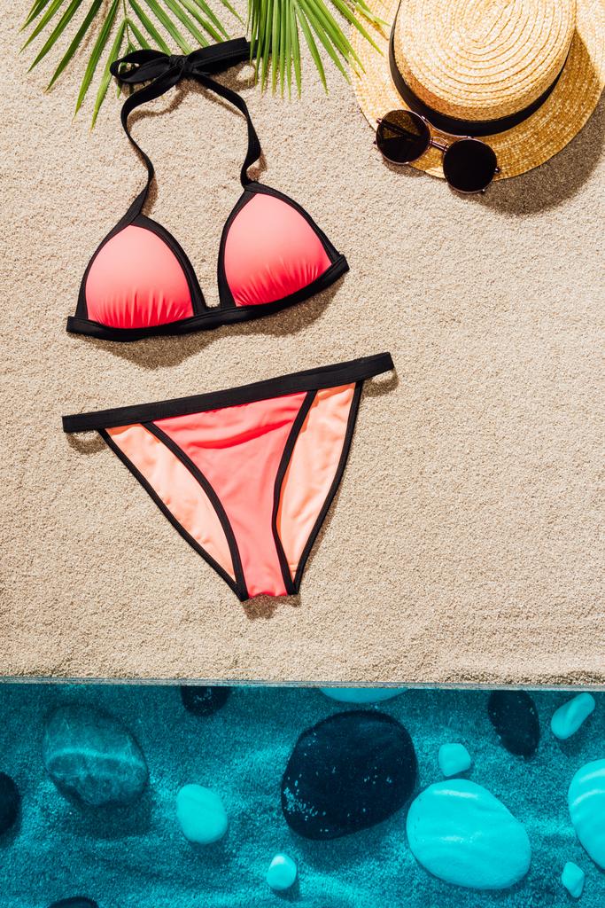 Blick von oben auf stilvollen rosa Bikini mit Accessoires am Sandstrand - Foto, Bild
