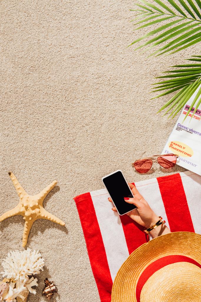обрізаний знімок жінки, використовуючи смартфон, відпочиваючи на піщаному пляжі
 - Фото, зображення