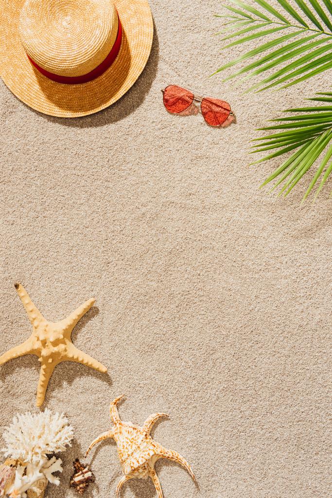 Draufsicht auf Strohhut mit Sonnenbrille am Sandstrand - Foto, Bild