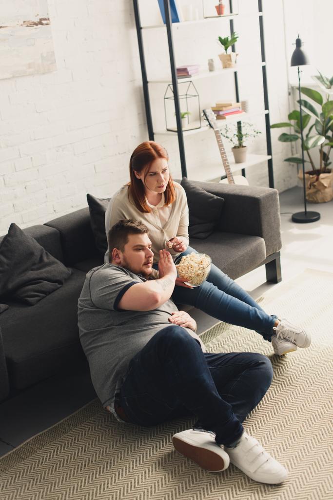 парень и девушка смотрят телевизор и едят попкорн дома
 - Фото, изображение