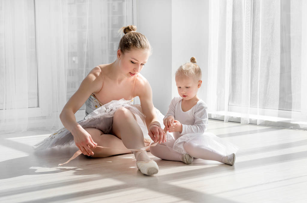 小さな女の子がバレエ トウシューズの結び方を教えています。 - 写真・画像