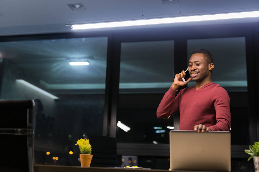 schwarzer Geschäftsmann mit Laptop in der Nacht arbeitet Überstunden stressiges Leben - Foto, Bild