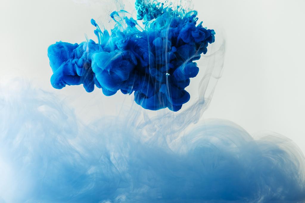 Close-up van het mengen van blauw en lichtblauw schildert spatten in water geïsoleerd op grijs - Foto, afbeelding