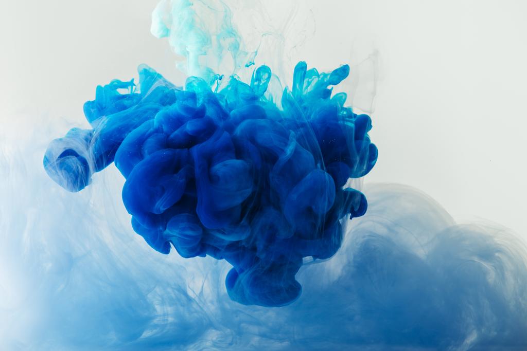 Zbliżenie, mieszania niebieski i turkusowy atrament plamy w wodzie na szarym tle - Zdjęcie, obraz