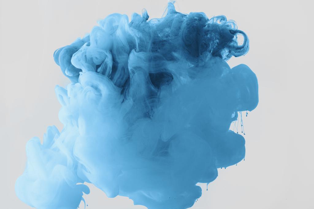 Close up view of mixing of bright pale blue and blue ink splashes in water isolated on gray - Photo, Image