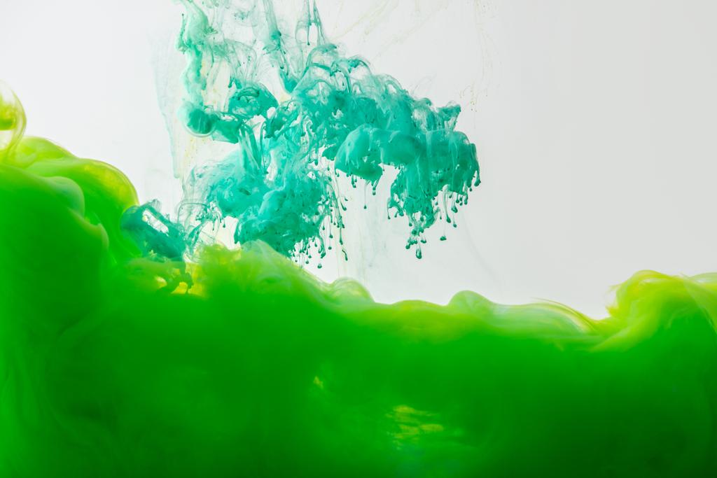 vista de cerca de la mezcla de pinturas turquesas verdes y brillantes salpicaduras en agua aislada en gris
 - Foto, imagen