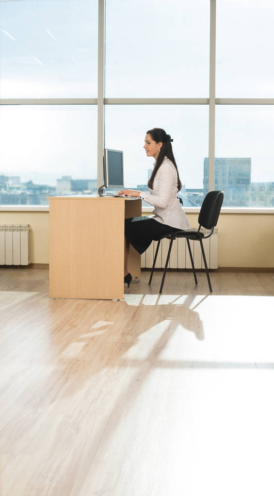 Jonge zakenvrouw zitten op kantoor tafel, personal computer kijken - Foto, afbeelding