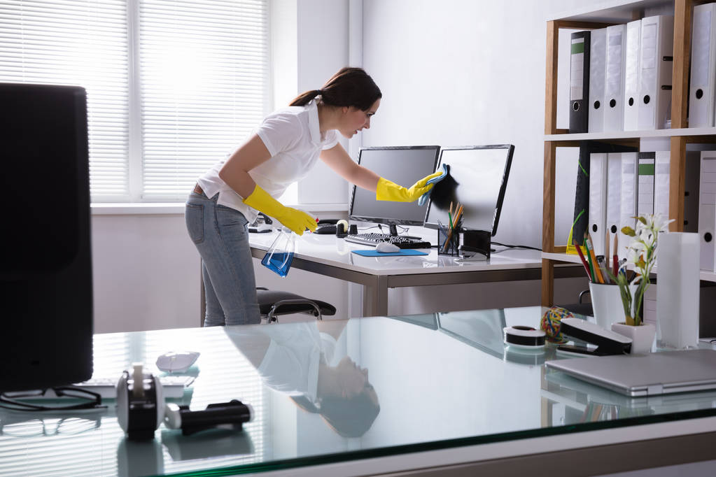 Νεαρή γυναίκα τον καθαρισμό του υπολογιστή με πανί στο γραφείο - Φωτογραφία, εικόνα