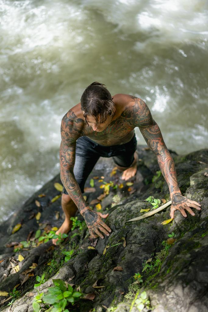 背景には、インドネシア ・ バリ島の川で岩に登って刺青男のオーバー ヘッド ビュー - 写真・画像