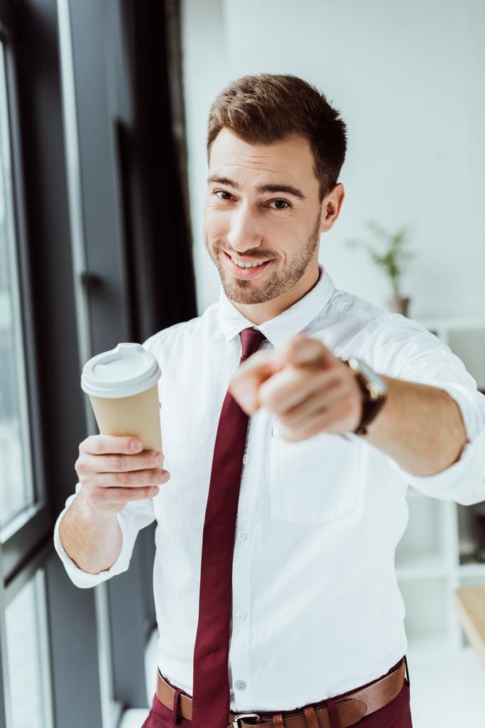 homme d'affaires souriant avec tasse de café jetable pointant vers vous
 - Photo, image