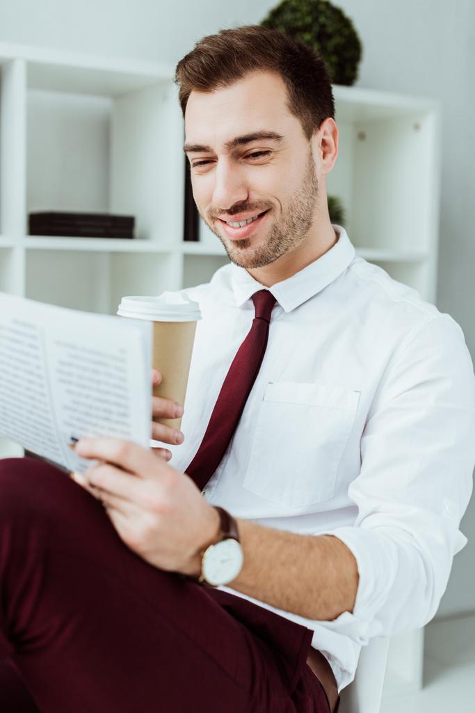 stijlvolle lachende zakenman met koffie te gaan lezen van krant in kantoor - Foto, afbeelding