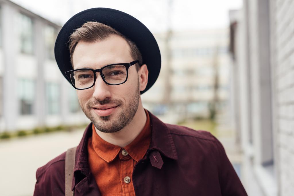 szép, mosolygós fiatalember, divatos kalap és szemüvegek - Fotó, kép