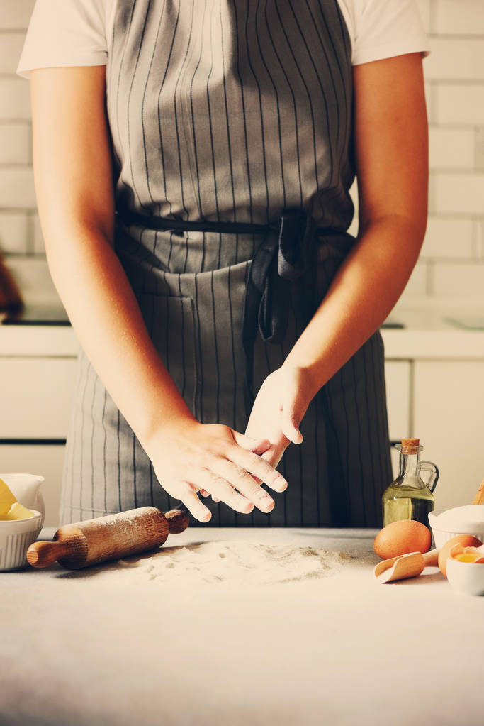 Female hands kneading dough, baking background. Cooking ingredients - eggs, flour, sugar, butter, milk, rolling pin on white style kitchen. Copy space - Photo, Image