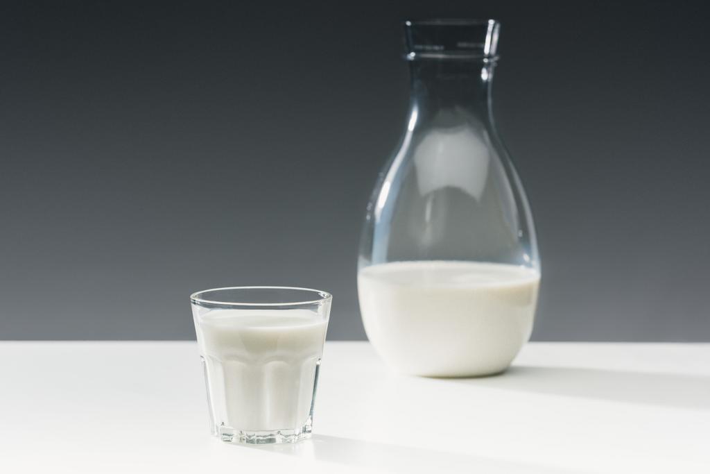 Γάλα σε γυαλί και μπουκάλι σε πίνακα σε γκρίζο φόντο - Φωτογραφία, εικόνα