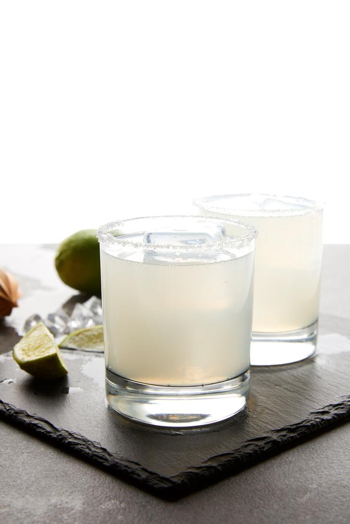 Close up view of refreshing caipirinha cocktails with lime on tabletop on white - Photo, Image