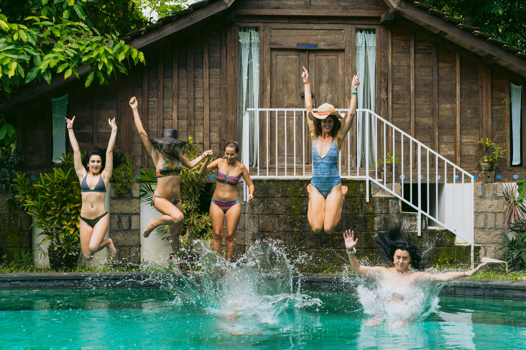 belles jeunes femmes en maillots de bain sautant dans la piscine de la station tropicale
  - Photo, image